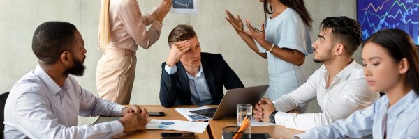 Business Conflicts. Two Female Employees Arguing During Corporate Meeting In Office, Multiethnic Group Of Business People Having Stress With New Project, Brainstorming Together In Boardroom