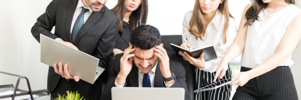 Stressed businessman unable to cope with too much work assigned by colleagues in office