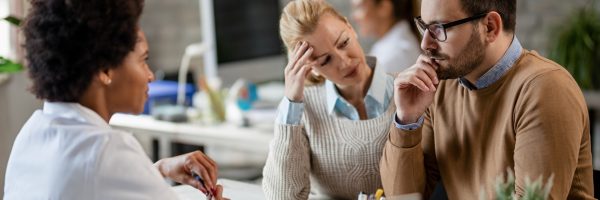Young couple feeling worried after talking to an African American doctor during medical appointment.