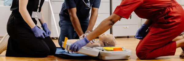 Diverse group of medical students practicing cpr on a medical manikin during first aid training in a hospital or clinic setting